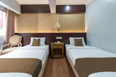 a hotel room with two beds and a chair at Hotel grand orchard in Kuala Lumpur