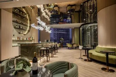 a restaurant with a bar with green chairs and wine bottles at St Giles Gardens Residences Kuala Lumpur in Kuala Lumpur