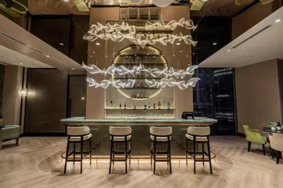 a bar in a restaurant with stools and a chandelier at St Giles Gardens Residences Kuala Lumpur in Kuala Lumpur