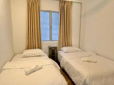 two beds in a room with a window at 3 bedroom apt L21 in kl sentral with city view in Kuala Lumpur