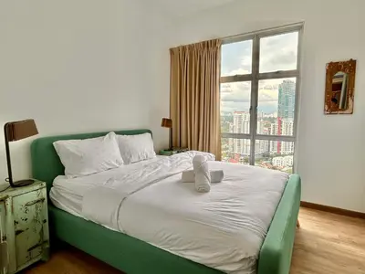 a bedroom with a green bed with a teddy bear on it at 3 bedroom apt L26 at kl sentral with city view in Kuala Lumpur
