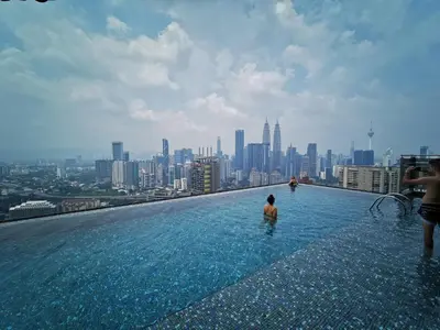a man in a infinity pool on the roof of a building at EXPRESSIONZ DESIGNER SUITES Host By AURORA PREMIUM STAY in Kuala Lumpur