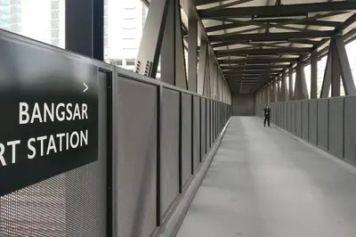 a man walking down a bridge with a sign on it at 3min Bangsar LRT-1 Station to KL Sentral-SuperView in Kuala Lumpur