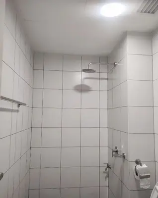 a white tiled bathroom with a shower with a light at The Luxe Stay Chamber KL in Kuala Lumpur