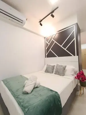 a white bedroom with a bed with a green blanket at COL 108A Modern KLCC Balcony View & Infinity Pool in Kuala Lumpur