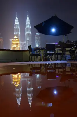 a table with chairs and an umbrella with a city skyline at Redstone Boutique Hotel Kuala Lumpur in Kuala Lumpur