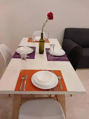 a table with white plates and a vase with a flower at VORTEX SUITS KLCC by MMHB in Kuala Lumpur