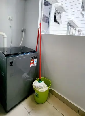 a mop in a bucket next to a washing machine at Cheras MRT KLCC View Home by DefineSuite in Kuala Lumpur