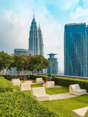 a park with white chairs and tall buildings at The Mews KLCC, Five Senses in Kuala Lumpur