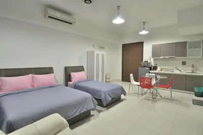 a bedroom with two beds and a table and a kitchen at BEST KL City View at Regalia Residence in Kuala Lumpur