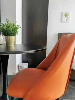 a table and two orange chairs in a room at Scarletz Suites KLCC by De Harlequins Suite in Kuala Lumpur