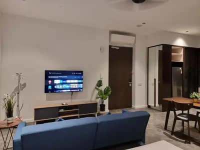 a living room with a blue couch and a tv at Scarletz Suites KLCC by De Harlequins Suite in Kuala Lumpur