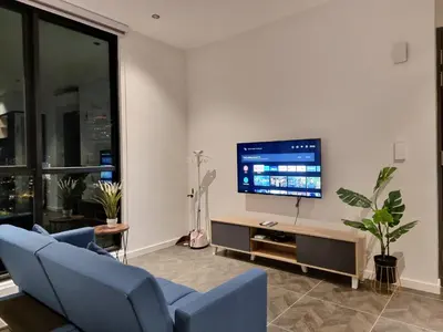 a living room with a blue couch and a flat screen tv at Scarletz Suites KLCC by De Harlequins Suite in Kuala Lumpur