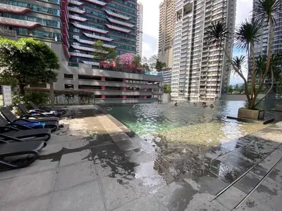 a pool with chairs and palm trees and buildings at Cemara Premier Residence Ampang Near KLCC Kuala Lumpur in Kuala Lumpur