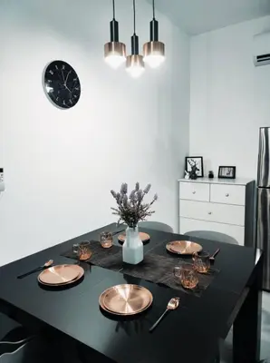 a dining room table with plates and a clock on the wall at Neu Suites Cozy Family House KLCC in Kuala Lumpur