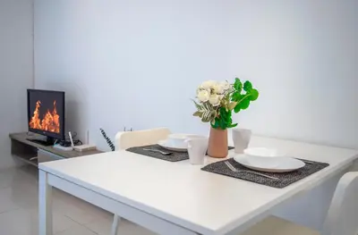a white table with two plates and a vase with flowers at Carlton, Chelsea at Plaza Damas 3, Sri Hartamas Kuala Lumpur in Kuala Lumpur