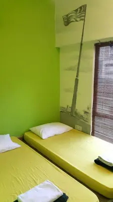 two beds in a room with green walls at PODs The Backpackers Home & Cafe, Kuala Lumpur in Kuala Lumpur