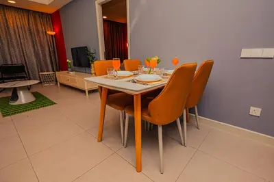 a dining room with a table and orange chairs at The Atrium at Jalan Ampang by OKBnB - Cozy 2 Bedroom, 3 mins to KLCC in Kuala Lumpur