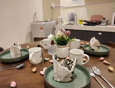 a table with plates and cups and flowers on it at KL Midvalley LRT Bangsar Modern BTC12 D in Kuala Lumpur