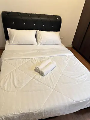 a white bed with a black headboard and a towel on it at The E48-10 Stay in Kuala Lumpur