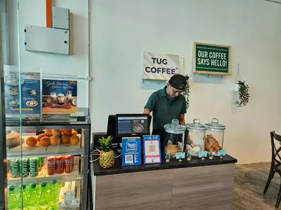 a man standing at a counter in a coffee shop at SerenityStayatRiveria KL Sentral in Kuala Lumpur
