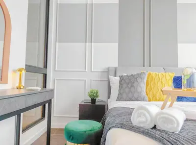 a bedroom with a bed with a green stool at Scarletz Suites KLCC by WSD in Kuala Lumpur