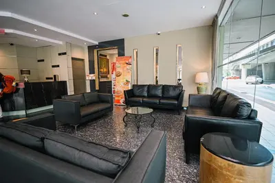 a living room with black leather couches and a table at Kingston Hotel 11 - PWTC, KL in Kuala Lumpur