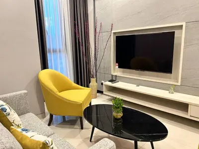 a living room with a tv and a table and yellow chairs at Societe by Bamboo Hospitality in Kuala Lumpur