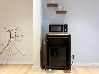 a microwave sitting on top of a wooden stand next to a wall at Japandi Studio w Bathtub - Linked to Quill City Mall in Kuala Lumpur