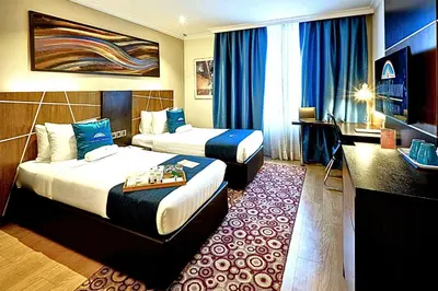 a hotel room with two beds with blue curtains at Howard Johnson By Wyndham Kuala Lumpur 118 in Kuala Lumpur