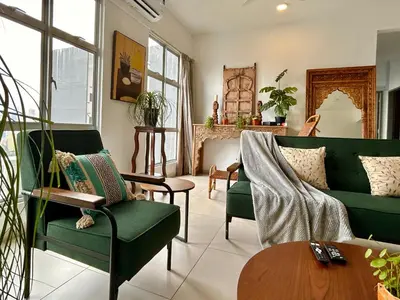 a living room with green couches and a table at 3BR Vintage design Level 26, KL Sentral City View in Kuala Lumpur