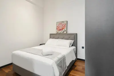 a bedroom with a large bed with white sheets at Luxe Suite in Kuala Lumpur