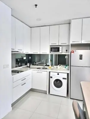 a kitchen with white cabinets and a washer and dryer at Mercu Summer Suites KL City Centre in Kuala Lumpur