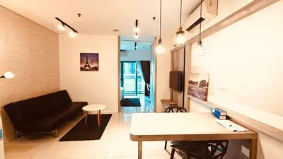 a living room with a black couch and a table at Mercu Summer Suites KL City Centre in Kuala Lumpur