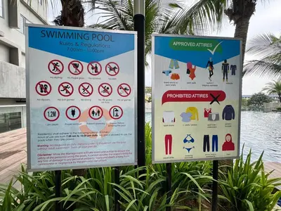 two signs on poles in front of a body of water at Peaceful 3BR 2B with Pool 10pax Wangsa Maju near Wangsa Walk in Kuala Lumpur