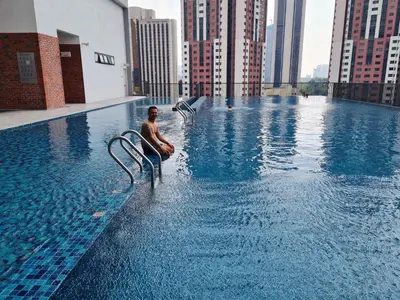a man sitting in a swimming pool on top of a building at Chambers Suites KL By 969 in Kuala Lumpur