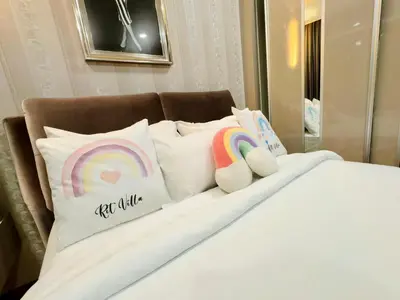 a bed with pillows with a rainbow and two stuffed animals at Vortex Suites Yonder Twin Tower in Kuala Lumpur