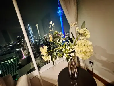 a vase of flowers on a table in a room with a window at Vortex Suites Yonder Twin Tower in Kuala Lumpur