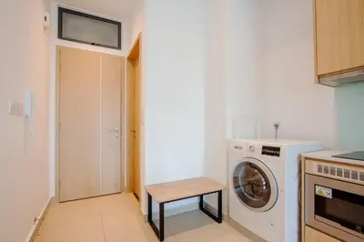 a small kitchen with a washing machine and a stool at LUXE Infinitum KLCC by DX in Kuala Lumpur