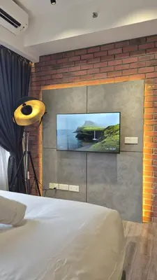a bedroom with a tv on a brick wall at Agile Pavillion TRX Luxury Suited Kuala Lumpur Good View in Kuala Lumpur