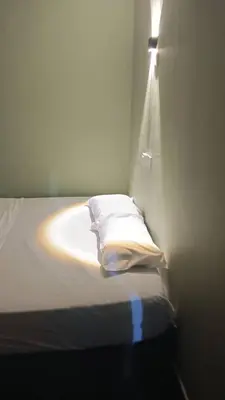 a bedroom with a bed with a light on the wall at Health Homestay KL in Kuala Lumpur