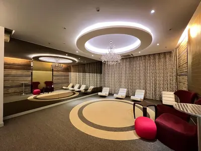 a lobby with a waiting room with red chairs and a chandelier at Empire Hostel Regalia in Kuala Lumpur