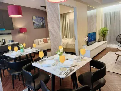 a dining room with two tables and chairs and a living room at The Atrium at Jalan Ampang by OKBnB - Modern Stylish 2Bedroom with FREE WiFi and Carpark in Kuala Lumpur