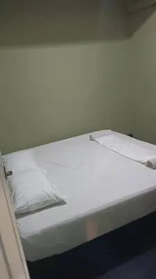 a white bed with white sheets and pillows on it at Health Homestay KL in Kuala Lumpur