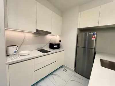 a kitchen with white cabinets and a stainless steel refrigerator at Alfa Bangsar by The Homez in Kuala Lumpur