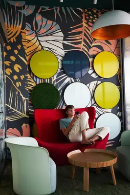 a man sitting on a red couch in front of a colorful wall at Riveria City, Kl Sentral Studio Apartment near Monorail, Infinity Pool in Kuala Lumpur