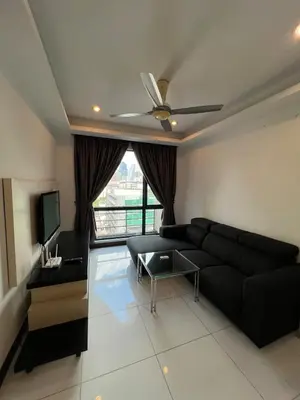 a living room with a black couch and a tv at Casa Residency in Bukit in Kuala Lumpur