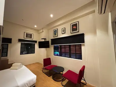 a bedroom with a bed and two red chairs at Star Mews Hotel Changkat Bukit Bintang in Kuala Lumpur
