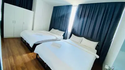 two beds in a hotel room with black curtains at Summer Suites by Western Holiday in Kuala Lumpur