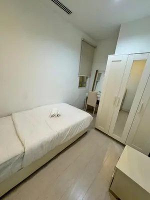 a white bedroom with a bed and a cabinet at Cosy 2-bedroom KLCC in Kuala Lumpur